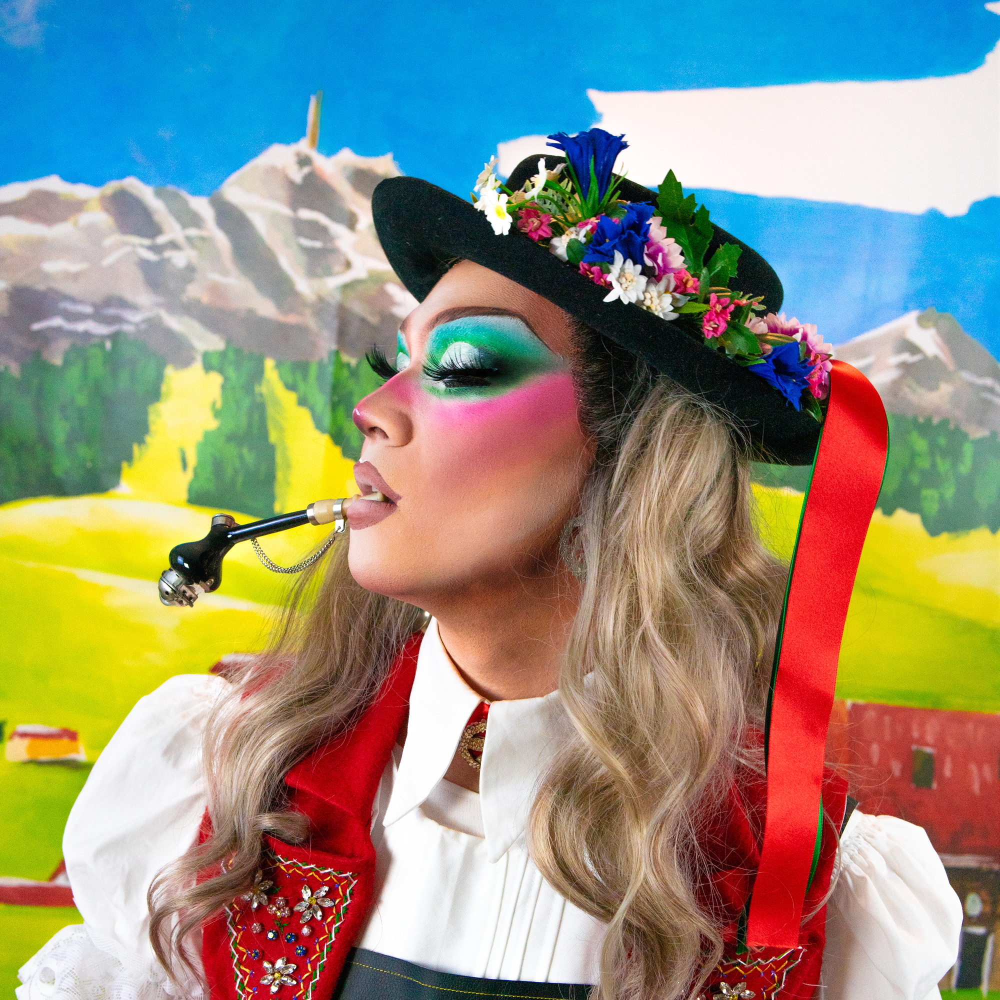 Third Kylie, Drag Queen aus Zürich in einem Kostüm inspiriert von einem Appenzeller Senn vor einem selbstgemalten Hintergrund mit dem Säntis